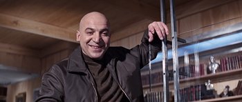 Movie still from “On Her Majesty's Secret Service” (1969), directed by Peter R. Hunt – A man with bald head holding a metal rod; Medium shot, Low angle