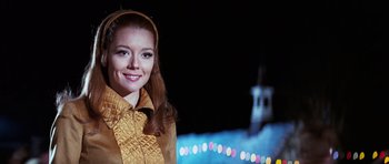 Movie still from “On Her Majesty's Secret Service” (1969), directed by Peter R. Hunt – A woman in a yellow jacket standing in front of lights; Close Up shot, Low angle