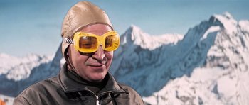 Movie still from “On Her Majesty's Secret Service” (1969), directed by Peter R. Hunt – A man wearing goggles and a hat in front of a mountain; Close Up shot, Low angle