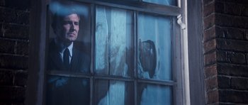 Movie still from “On Her Majesty's Secret Service” (1969), directed by Peter R. Hunt – A man in a suit looking out of a window; Medium shot, Low angle