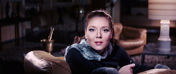 Movie still from “On Her Majesty's Secret Service” (1969), directed by Peter R. Hunt – A woman sitting on a couch wearing a fur collar; Close Up shot, Low angle