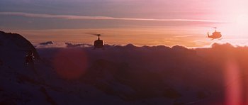 Movie still from “On Her Majesty's Secret Service” (1969), directed by Peter R. Hunt – A helicopter is flying over the clouds at sunset; Extreme Wide shot, Low angle