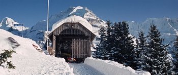 Movie still from “On Her Majesty's Secret Service” (1969), directed by Peter R. Hunt – A wooden shed sitting in the middle of a snow covered field; Extreme Wide shot, Low angle