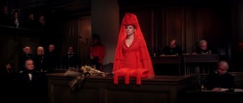 Movie still from “On a Clear Day You Can See Forever” (1970), directed by Vincente Minnelli – A woman in a red dress sitting in front of a wooden table; Medium shot, Low angle