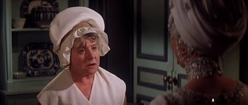 Movie still from “On a Clear Day You Can See Forever” (1970), directed by Vincente Minnelli – An older woman wearing a white hat talking to another woman; Close Up shot, Over the shoulder angle