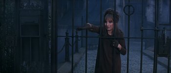 Movie still from “On a Clear Day You Can See Forever” (1970), directed by Vincente Minnelli – A woman standing behind a fence in a dark place; Medium shot, High angle