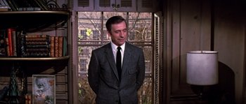 Movie still from “On a Clear Day You Can See Forever” (1970), directed by Vincente Minnelli – A man wearing a suit and tie standing in front of a window; Medium shot, Low angle