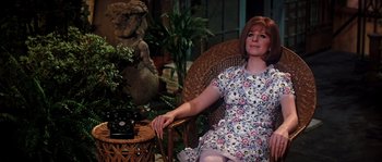 Movie still from “On a Clear Day You Can See Forever” (1970), directed by Vincente Minnelli – A woman sitting in a chair next to an old fashioned phone; Medium shot, High angle