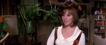 Movie still from “On a Clear Day You Can See Forever” (1970), directed by Vincente Minnelli – A woman wearing a plaid hat standing next to a tree; Medium shot, Over the shoulder angle