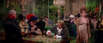 Movie still from “On a Clear Day You Can See Forever” (1970), directed by Vincente Minnelli – A group of people sitting at a table playing a board game; Wide shot, High angle
