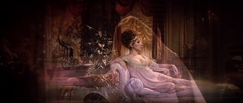 Movie still from “On a Clear Day You Can See Forever” (1970), directed by Vincente Minnelli – A woman sitting on top of a couch in front of a tree; Wide shot, High angle