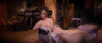 Movie still from “On a Clear Day You Can See Forever” (1970), directed by Vincente Minnelli – A woman sitting on top of a couch in a room; Medium shot, High angle