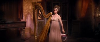 Movie still from “On a Clear Day You Can See Forever” (1970), directed by Vincente Minnelli – A woman in a dress standing in front of a harp; Medium shot, High angle