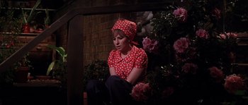 Movie still from “On a Clear Day You Can See Forever” (1970), directed by Vincente Minnelli – A woman sitting on the ground in front of flowers; Medium shot, High angle