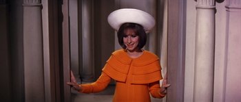 Movie still from “On a Clear Day You Can See Forever” (1970), directed by Vincente Minnelli – A woman wearing an orange dress and a white hat; Medium shot, High angle