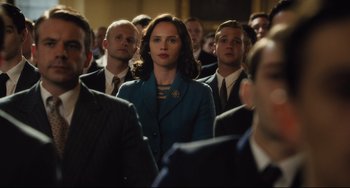 Movie still from “On the Basis of Sex” (2018), directed by Mimi Leder – A group of people standing in a room; Medium shot, Over the shoulder angle