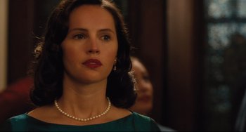 Movie still from “On the Basis of Sex” (2018), directed by Mimi Leder – A woman wearing a green dress and a pearl necklace; Close Up shot, Over the shoulder angle