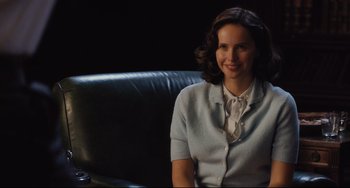 Movie still from “On the Basis of Sex” (2018), directed by Mimi Leder – A woman sitting in a chair smiling for the camera; Medium shot, Over the shoulder angle