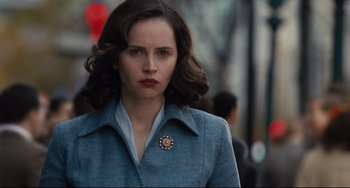 Movie still from “On the Basis of Sex” (2018), directed by Mimi Leder – A woman in a blue coat is walking down the street; Close Up shot, Over the shoulder angle