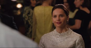 Movie still from “On the Basis of Sex” (2018), directed by Mimi Leder – A woman in a white dress is standing in front of a group of people; Close Up shot, Over the shoulder angle