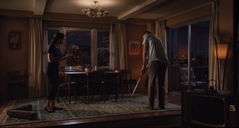 Movie still from “On the Basis of Sex” (2018), directed by Mimi Leder – An older man playing a game of golf in a living room; Wide shot, High angle