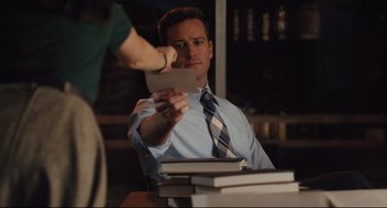 Movie still from “On the Basis of Sex” (2018), directed by Mimi Leder – A man sitting at a table holding a piece of paper; Medium shot, Over the shoulder angle