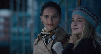 Movie still from “On the Basis of Sex” (2018), directed by Mimi Leder – A woman in a trench coat standing next to another woman; Close Up shot, Over the shoulder angle
