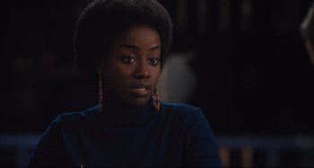 Movie still from “On the Basis of Sex” (2018), directed by Mimi Leder – A black woman wearing a blue shirt and brown earrings; Close Up shot, Over the shoulder angle