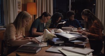 Movie still from “On the Basis of Sex” (2018), directed by Mimi Leder – A group of people sitting at a table reading books; Medium shot, High angle