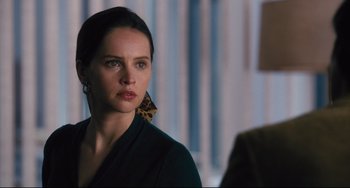 Movie still from “On the Basis of Sex” (2018), directed by Mimi Leder – A woman wearing a black shirt and a leopard print earring; Close Up shot, Over the shoulder angle