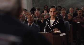 Movie still from “On the Basis of Sex” (2018), directed by Mimi Leder – A woman is speaking at a podium in front of an audience; Medium shot, Over the shoulder angle