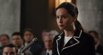 Movie still from “On the Basis of Sex” (2018), directed by Mimi Leder – A woman in a black and white jacket is speaking; Close Up shot, Over the shoulder angle