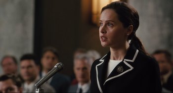 Movie still from “On the Basis of Sex” (2018), directed by Mimi Leder – A woman is speaking at a podium in front of a crowd; Close Up shot, Over the shoulder angle