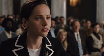 Movie still from “On the Basis of Sex” (2018), directed by Mimi Leder – A woman in black jacket looking at the camera; Close Up shot, Over the shoulder angle