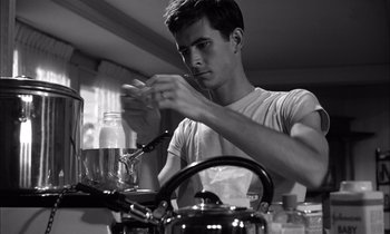 Movie still from “On the Beach” (1959), directed by Stanley Kramer – A young man preparing a meal in a kitchen; Medium shot, Low angle