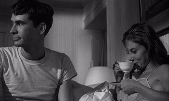 Movie still from “On the Beach” (1959), directed by Stanley Kramer – A man and a woman sitting on a bed drinking coffee; Medium shot, High angle