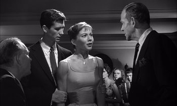 Movie still from “On the Beach” (1959), directed by Stanley Kramer – A group of people standing around each other in a room; Medium shot, Over the shoulder angle