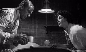 Movie still from “On the Beach” (1959), directed by Stanley Kramer – A man and a woman sitting at a dinner table; Medium shot, Low angle
