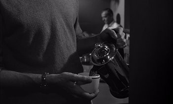 Movie still from “On the Beach” (1959), directed by Stanley Kramer – A man pouring a cup of coffee into a coffee pot; Medium shot, High angle