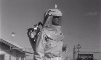 Movie still from “On the Beach” (1959), directed by Stanley Kramer – A man in a spacesuit with a gas mask on; Medium shot, Low angle