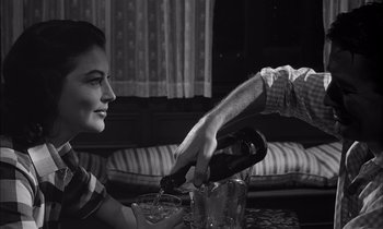 Movie still from “On the Beach” (1959), directed by Stanley Kramer – A man pouring a woman a glass of wine into a bucket; Medium shot, Over the shoulder angle