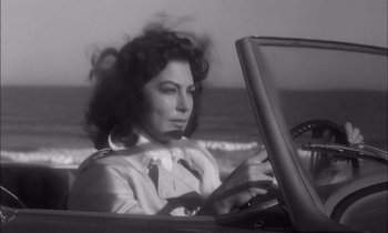 Movie still from “On the Beach” (1959), directed by Stanley Kramer – A black and white photo of a woman sitting in the back of a car looking at a computer; Close Up shot, Low angle