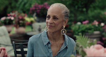 Movie still from “On the Rocks” (2020), directed by Sofia Coppola – An older woman wearing a blue shirt and gold jewelry; Close Up shot, Over the shoulder angle