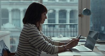 Movie still from “On the Rocks” (2020), directed by Sofia Coppola – A woman sitting at a table looking at her phone; Medium shot, Over the shoulder angle