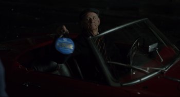 Movie still from “On the Rocks” (2020), directed by Sofia Coppola – An older man in a car holding a bottle of milk; Close Up shot, High angle