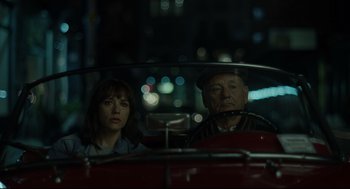 Movie still from “On the Rocks” (2020), directed by Sofia Coppola – A man and a woman sitting in a red car at night; Close Up shot, High angle