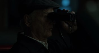 Movie still from “On the Rocks” (2020), directed by Sofia Coppola – An older man looking through a pair of binoculars; Close Up shot, Low angle