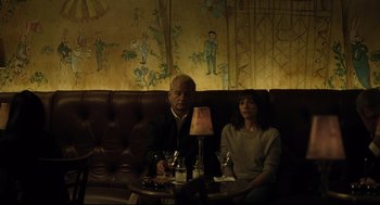 Movie still from “On the Rocks” (2020), directed by Sofia Coppola – A man and a woman sitting at a table in front of a lamp; Medium shot, High angle