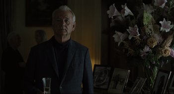 Movie still from “On the Rocks” (2020), directed by Sofia Coppola – An older man standing in a dark room; Medium shot, Over the shoulder angle