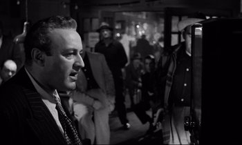 Movie still from “On the Waterfront” (1954), directed by Elia Kazan – A man standing in front of a group of people; Close Up shot, Over the shoulder angle